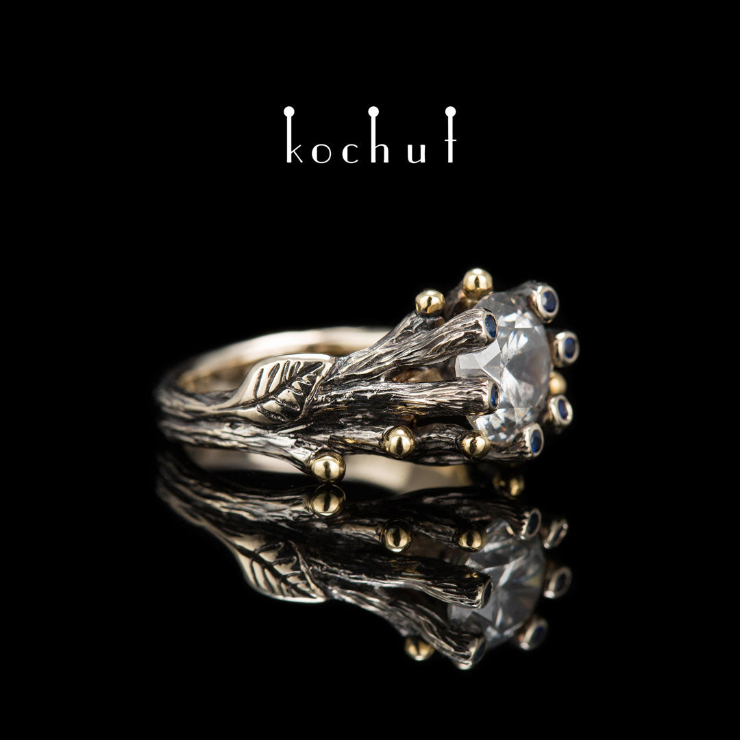Triumph des Lebens — Verlobungsring aus 18 Karat Weißgold und 14 Karat Gelbgold mit Diamanten und Saphiren, überzogen mit schwarzem Rhodium