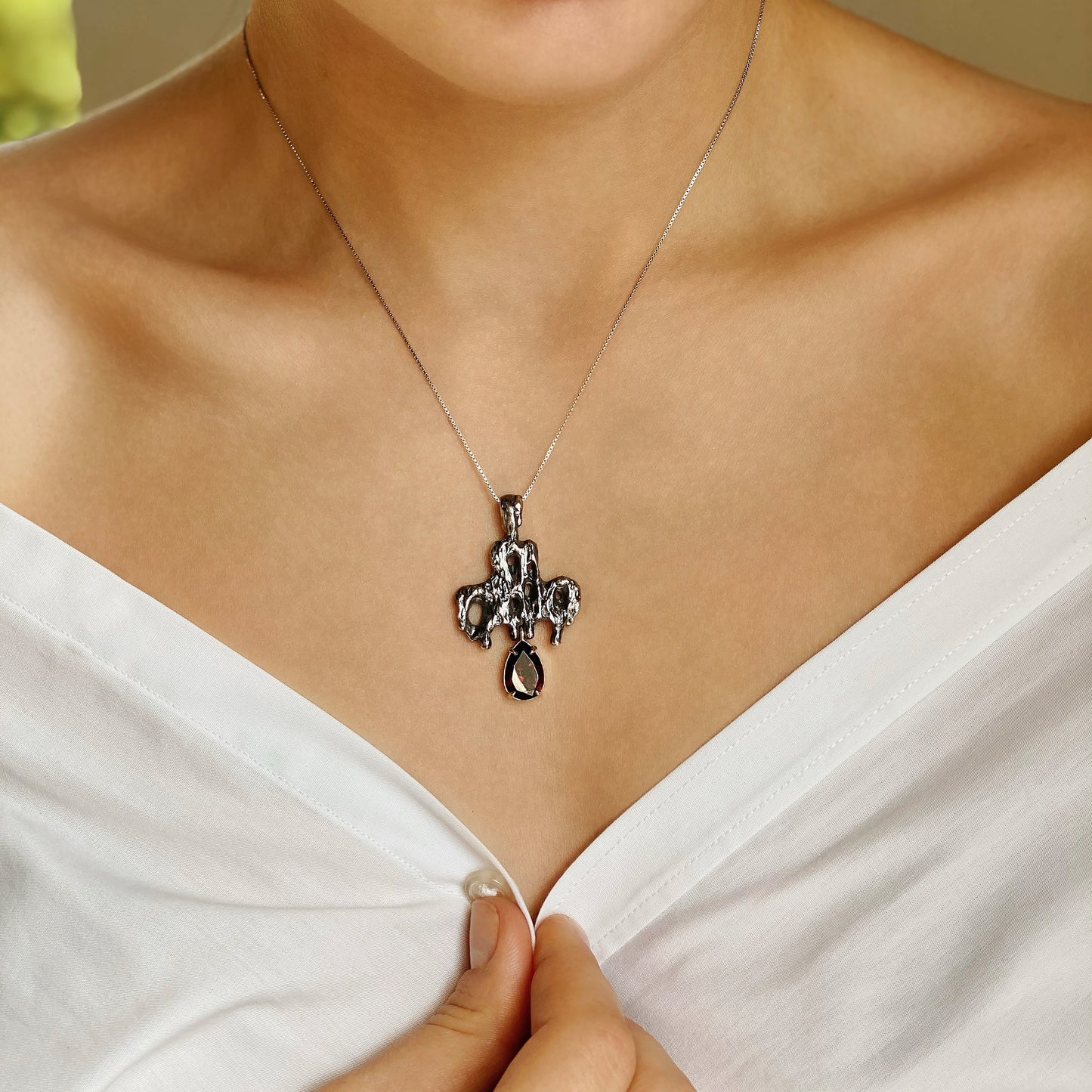 Memento mori — Kreuz aus oxidiertem Silber und Gelbgold mit einem Granat