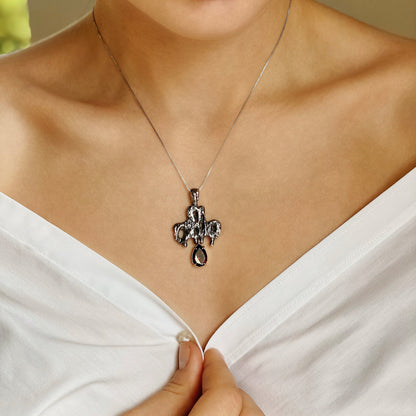 Memento mori — Kreuz aus oxidiertem Silber und Gelbgold mit einem Granat